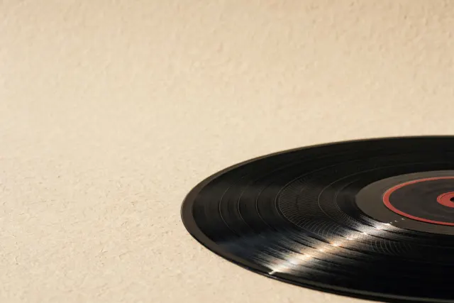 Makrofotografi av en matt svart vinylplate på varmt papir, der et så vidt synlig preget vannmerke i konsentriske ringer kun avsløres av en smal stribe av sidelys over sporene. Illustrasjon.