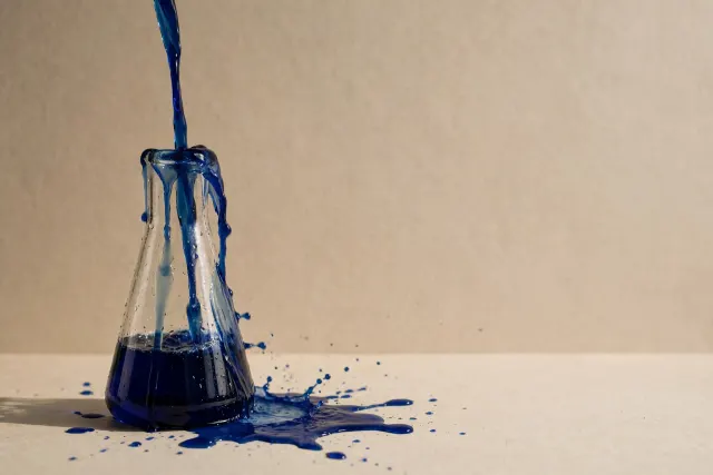 Illustration: a tall glass flask overflowing as liquid is poured in from above, in cobalt blue against a warm paper-toned backdrop.