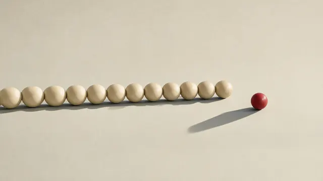 Illustration: a row of nearly identical ceramic spheres, one halted abruptly ahead of the others, evoking a relentless release pace meeting a call to slow down.