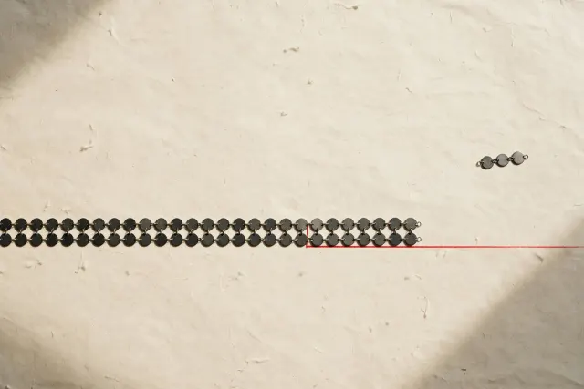 Illustration: a long row of small identical metal discs on paper, cut off at a single point, symbolizing a low token price with a limit.