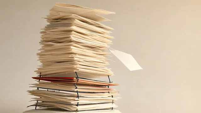 Illustration: a tall, unstable tower of paper sheets reinforced with thin steel rods at the base while the upper layers buckle and one sheet falls.