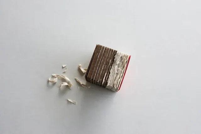 Illustration: A small, dense cube of layered wood and paper sits alone on a vast empty table, evoking a lightweight open model anyone can pick up and use.