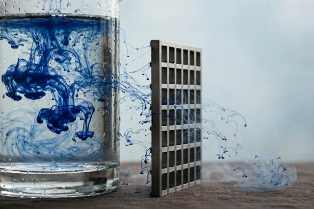 Illustration: swirling cobalt ink in water fails to pass through a precise metal grid, visualizing a turbulent fluid proof that does not match its formal verification code.