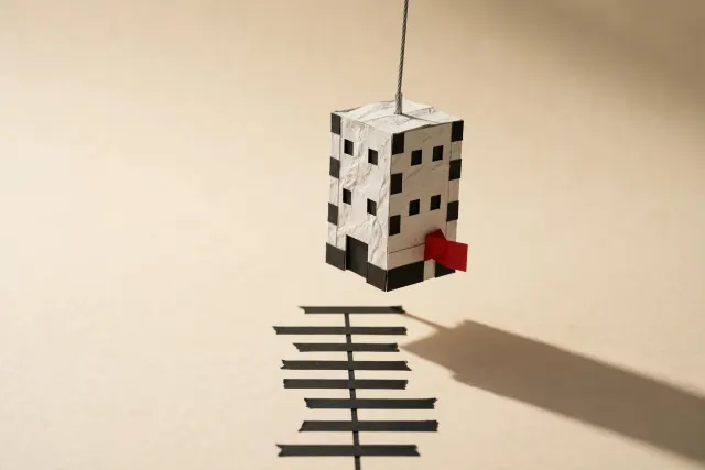 A small sculptural paper tower lifted by a thin steel cable over a cream surface, illustrating an acquisition and a sharp valuation jump.