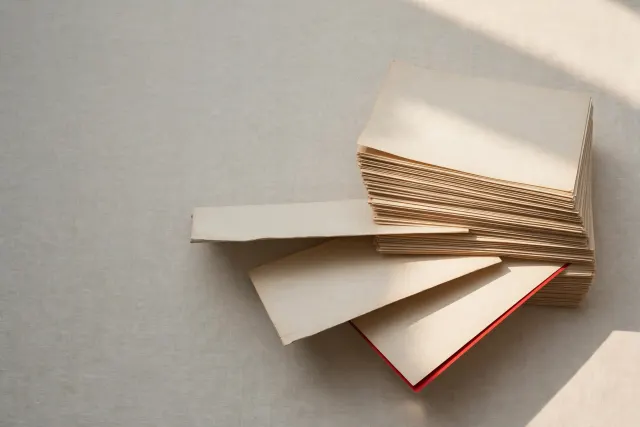 Illustration: A stack of nearly identical mathematics manuscripts with three sheets slipping out of alignment, in warm paper tones with one red detail.