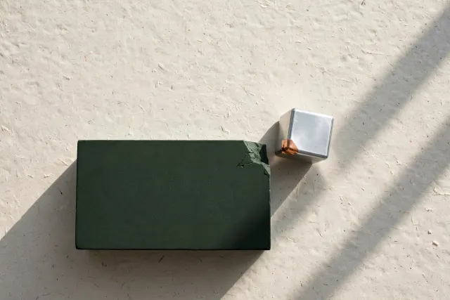Illustration: A large dark green slab and a small reflective metallic cube stand with a narrow gap between them, evoking an unconfirmed early-stage acquisition.