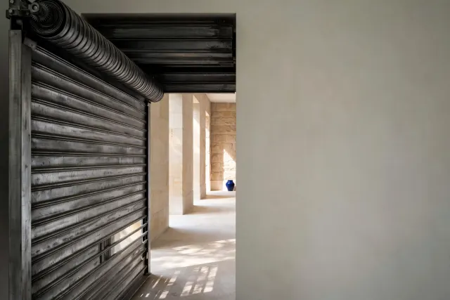 Illustration: A heavy steel roller shutter rolling up to open a doorway toward daylight, symbolizing restored access to AI models.