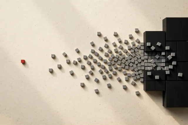 Illustration: Dozens of small gray cubes merging into a few large black blocks on a paper surface, with one red cube isolated in negative space — a picture of consolidation in the cybersecurity industry.