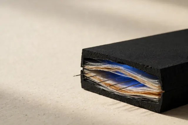 Illustration: a matte black block cut open to reveal translucent internal layers, with thin probe needles reading between them — a metaphor for monitoring an AI model's internal signals.
