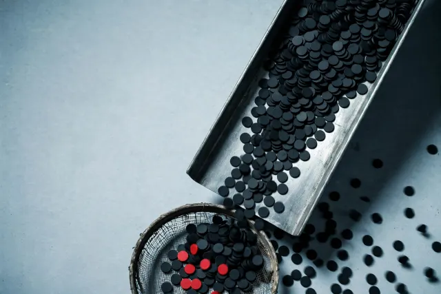 Illustration: Thousands of black tokens slide down a steel chute, with a worn mesh sieve catching only a few red tokens as the rest slip past.