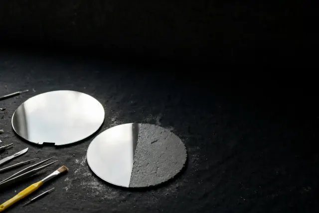 Illustration: two silicon wafers on a dark table, one fully polished and one unfinished, symbolizing a chipmaker awaiting its second major customer.