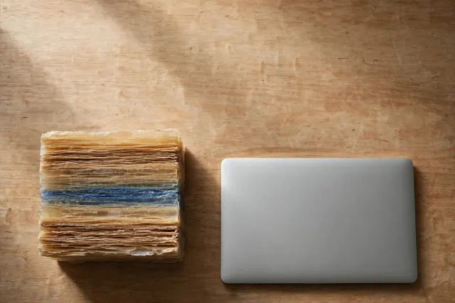 Illustration: a compact, compressed block of layered translucent material on a desk beside a closed laptop, symbolizing a quantized coding model running locally on user hardware.