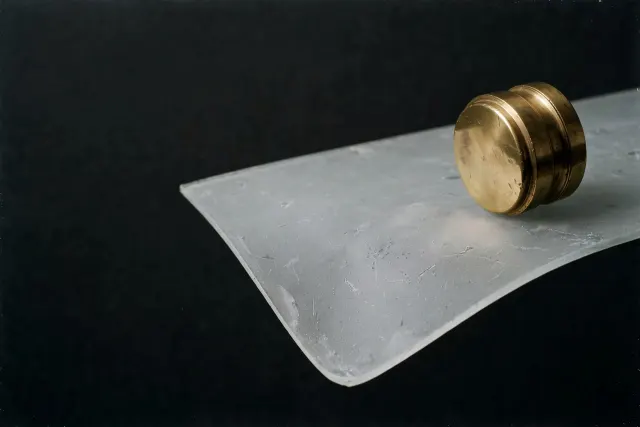 Illustration: A heavy brass weight rests on a frosted glass pane spanning a dark void — a picture of impressive financial figures resting on unverified support.